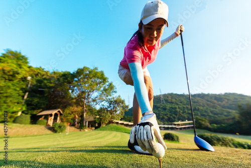 Hand of woman golf player gentle put a golf ball onto wooden tee on the tee off. Healthy and Lifestyle Concept.