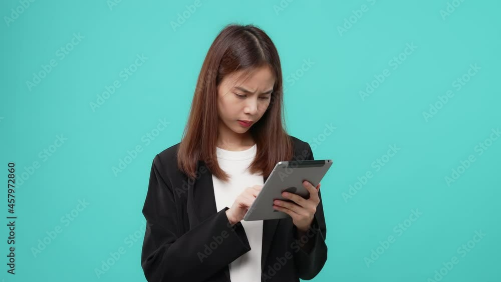 Young Asian woman holding digital tablet and smiling with touch on the screen, blue background Young Asian woman holding digital tablet and smiling with touch on the screen, blue background