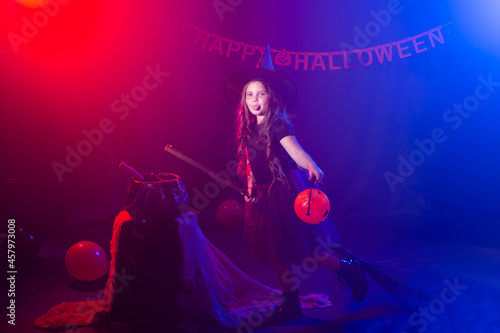 Funny child girl in witch costume for Halloween with pumpkin Jack and broom.