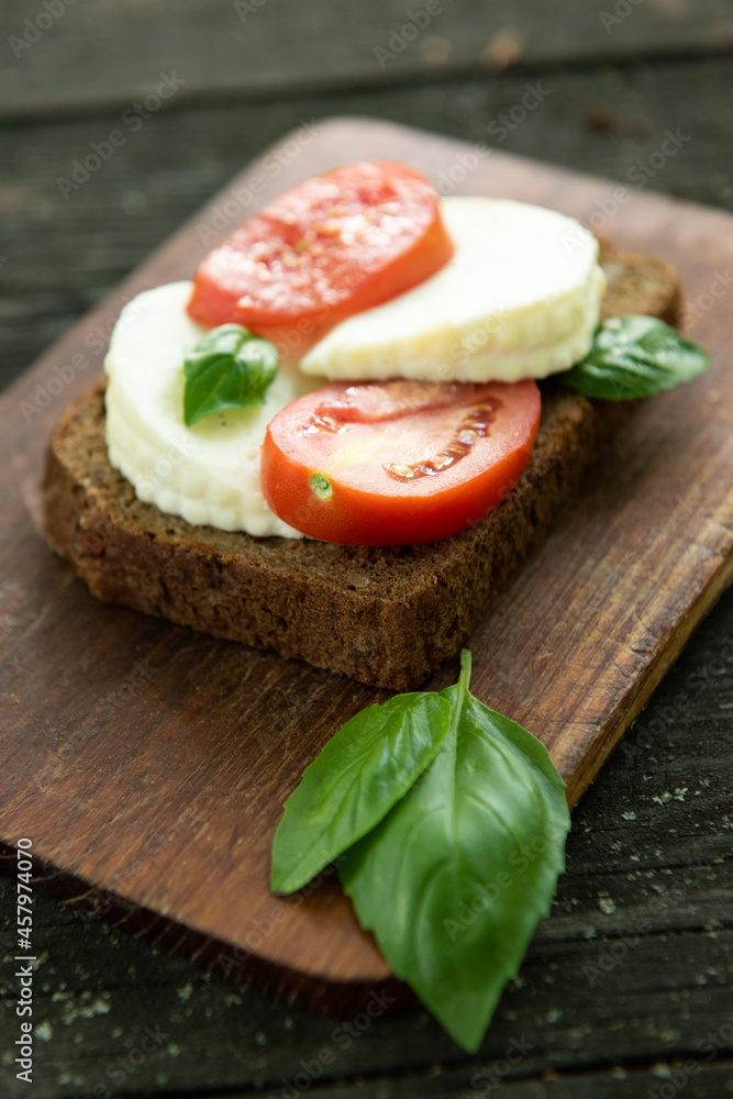 Sandwich with cheese, tomatoes and basil on a rustic wooden board. Healthy food. Food background Sandwich with cheese, tomatoes and basil on a rustic wooden board. Healthy food. Food background
