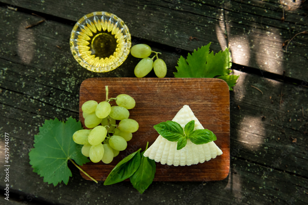 Cheese, Basil, Olive Oil, Grapes on dark background. Top view, flat lay Cheese, Basil, Olive Oil, Grapes on dark background. Top view, flat lay