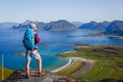 Woman hiker enjoying at the top of the mountain and looking at incredible views of a Norwegian fjord, Lofotens. Travel, adventure, healthy lifestyle concept