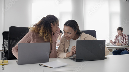Valokuva Female colleagues gossiping in office, friendly atmosphere at workplace, team