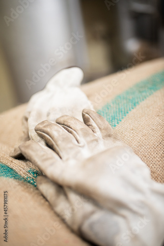 Close-up of coffee bag with glove on it. Bag made from burlap. Workman or workwoman glove. Production, industry, manufacturing process concept