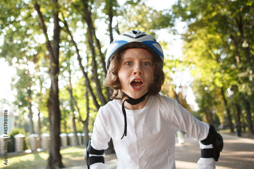 Excited young boy rollerblading at the park, wearing helmet Excited young boy rollerblading at the park, wearing helmet
