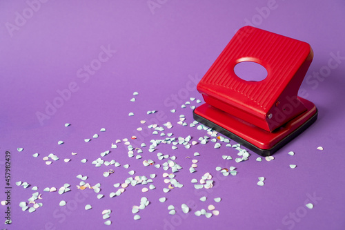 Red office paper hole puncher, isolated on purple background. Paper hole puncher machine.