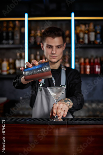 barman is making cocktail with steel shaker