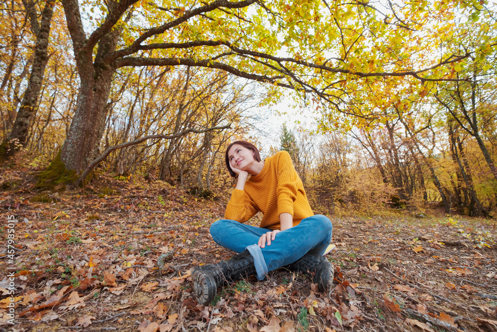 Woman hiking looking at scenic view of autumn foliage mountain landscape. Outdoor adventure travel lady sitting relaxing in nature in autumn season. Woman hiking looking at scenic view of autumn foliage mountain landscape. Outdoor adventure travel lady sitting relaxing in nature in autumn season.