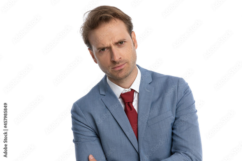 attractive young businessman in blue suit crossing arms and frowning attractive young businessman in blue suit crossing arms and frowning