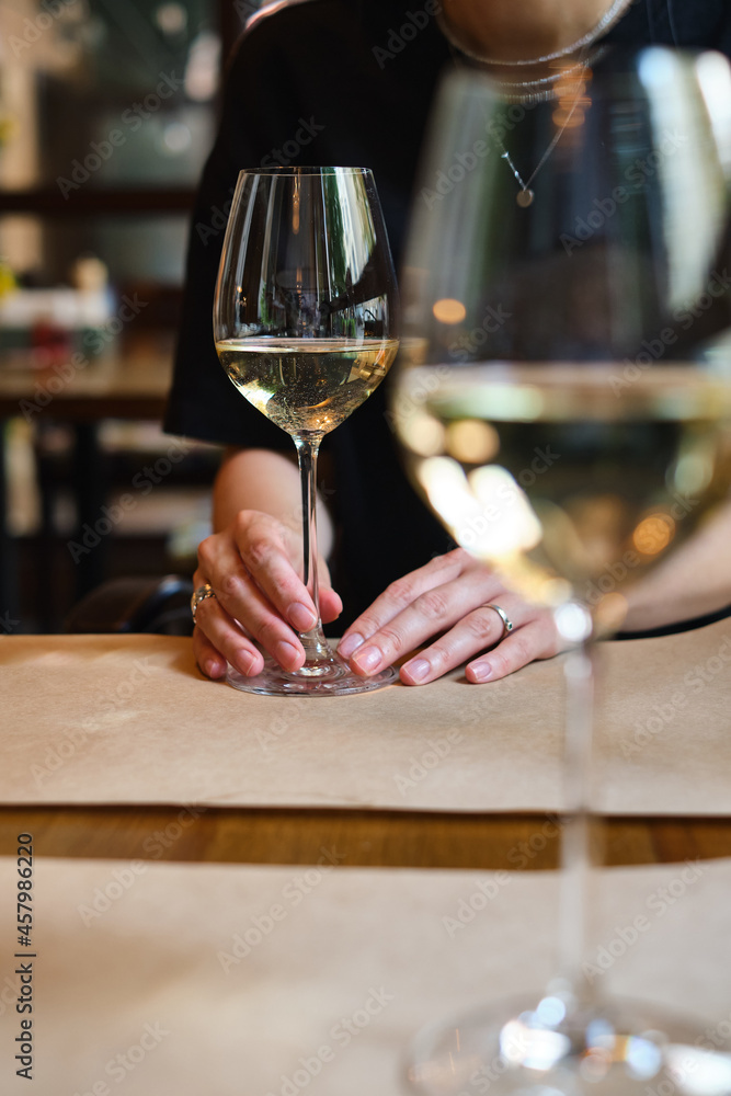 A glass of white wine in the hands of a girl relaxing in a restaurant. Tasting of alcoholic beverages. Summer rest. Romantic evening aperitif. Close-up of a glass of wine. Enjoy the moment A glass of white wine in the hands of a girl relaxing in a restaurant. Tasting of alcoholic beverages. Summer rest. Romantic evening aperitif. Close-up of a glass of wine. Enjoy the moment