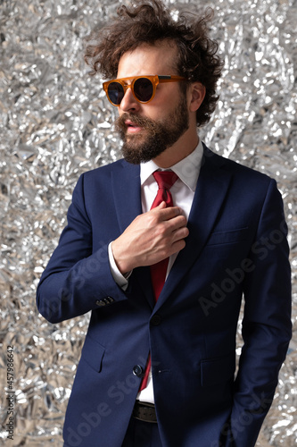 businessman adjusting his tie, holding one hand in pocket photo