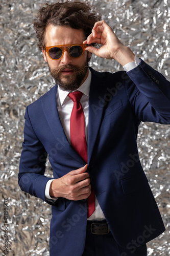 cool businessman fixing his sunglasses and adjusting his jacket photo