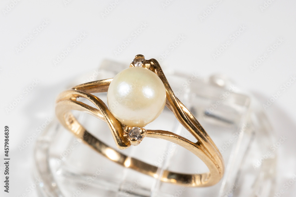 A gold ring with a white round pearl and two small diamonds A gold ring with a white round pearl and two small diamonds