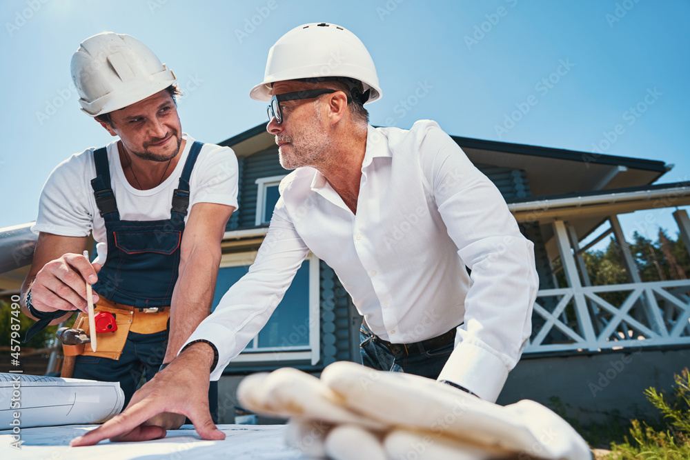 Mature engineer is consulting with younger colleague Mature engineer is consulting with younger colleague
