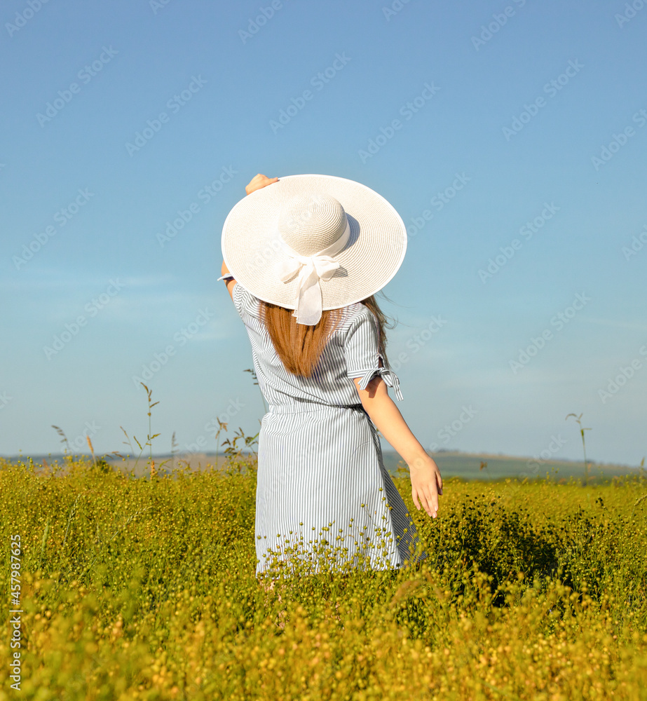 a young girl in a hat in a field in nature looks at the sky into the distance