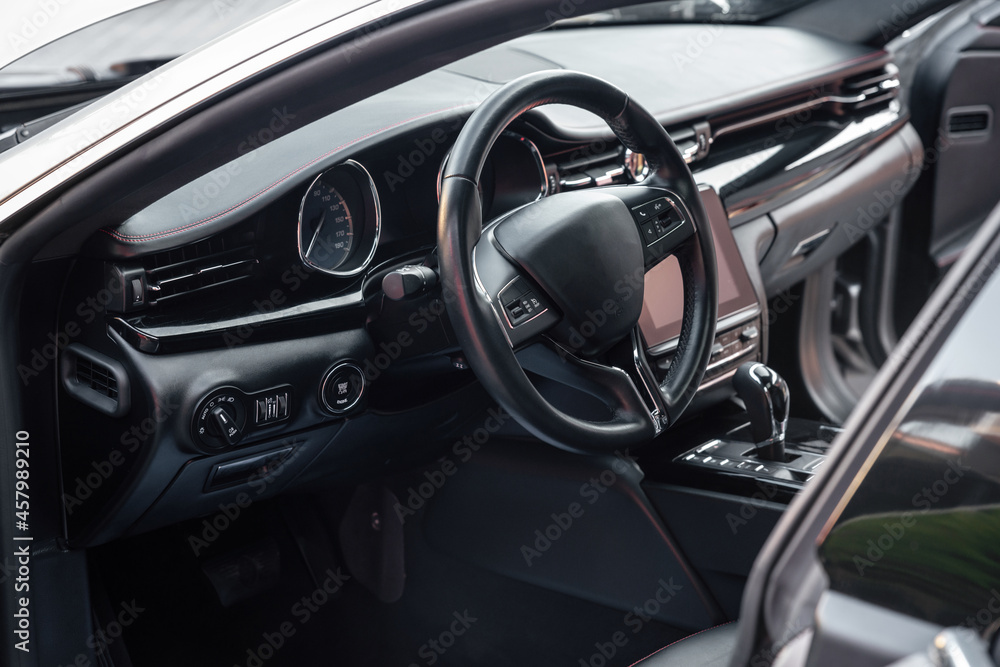 Car dashboard and steering wheel with media control buttons. Black cockpit. Luxury vehicle interior. Background on the theme of cars.