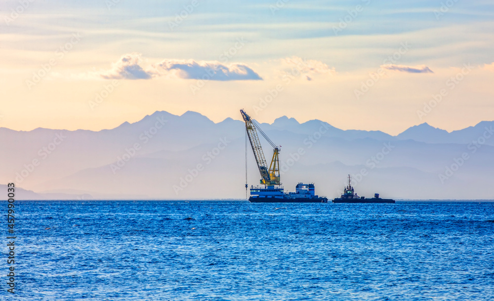 sea ship with a crane on the background of a mountain range in the haze sea ship with a crane on the background of a mountain range in the haze