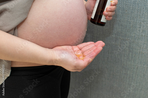 A young pregnant Asian woman applying body lotion not to make pregnancy stretch mark