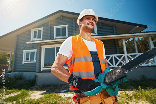 Man posing for photo with chainsaw near house photo