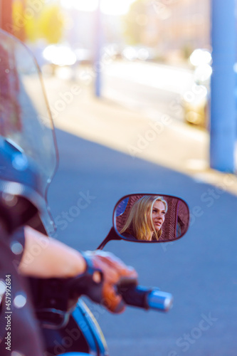 Mirror Reflection of Caucasian Sexy Female Biker in Black Bodysuit on Shiny New Bike On Street Outdoor.