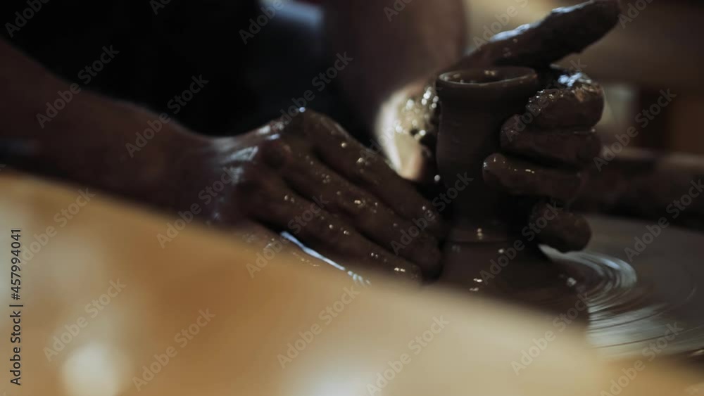 Close-up of the potter's hands stained in clay, creating a small glass or a shot on the potter's wheel. High quality 4k footage Close-up of the potter's hands stained in clay, creating a small glass or a shot on the potter's wheel. High quality 4k footage
