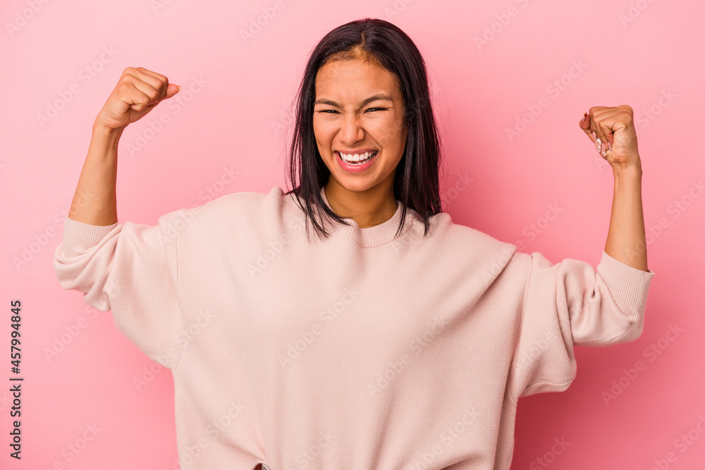 Young latin woman isolated on pink background showing strength gesture with arms, symbol of feminine power Young latin woman isolated on pink background showing strength gesture with arms, symbol of feminine power