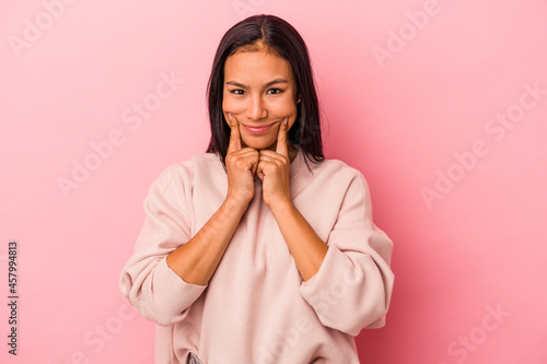 Young latin woman isolated on pink background doubting between two options.