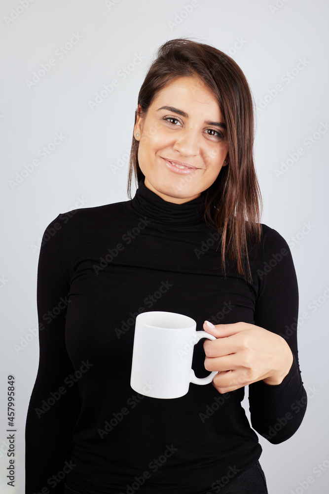 beautiful dark-skinned girl in a black turtleneck holding a mug and looking at the camera beautiful dark-skinned girl in a black turtleneck holding a mug and looking at the camera