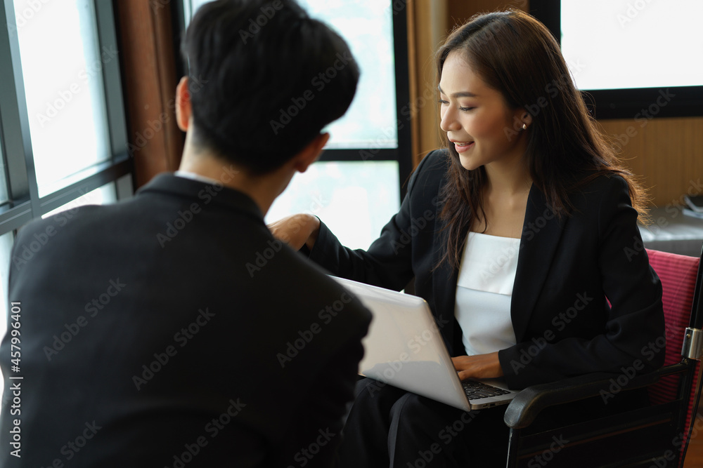 Asian businesswoman in wheelchair working with her colleagues Asian businesswoman in wheelchair working with her colleagues
