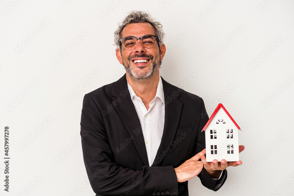 Middle age business man holding bills and house model isolated on blue background  laughing and having fun.