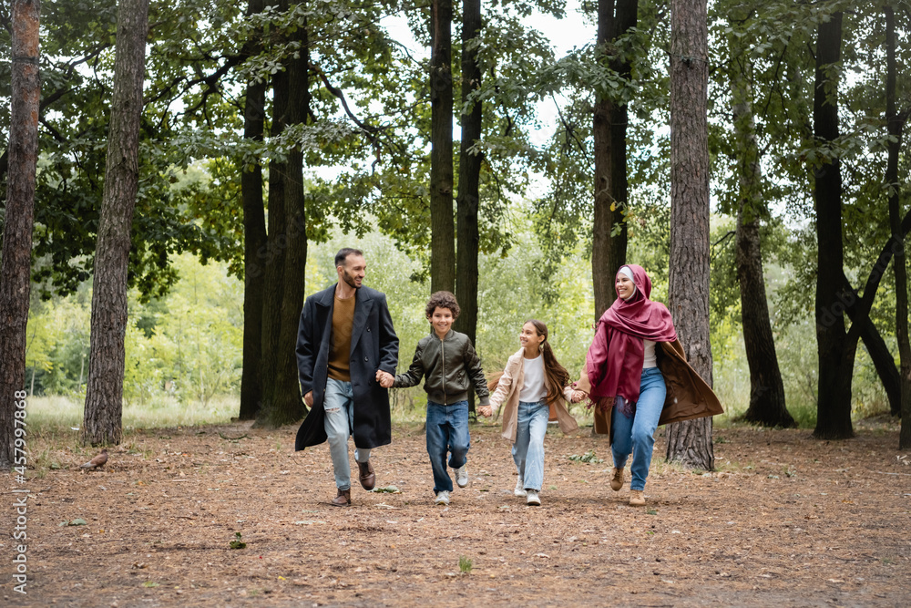 Happy arabian family holding hands while running in park Happy arabian family holding hands while running in park