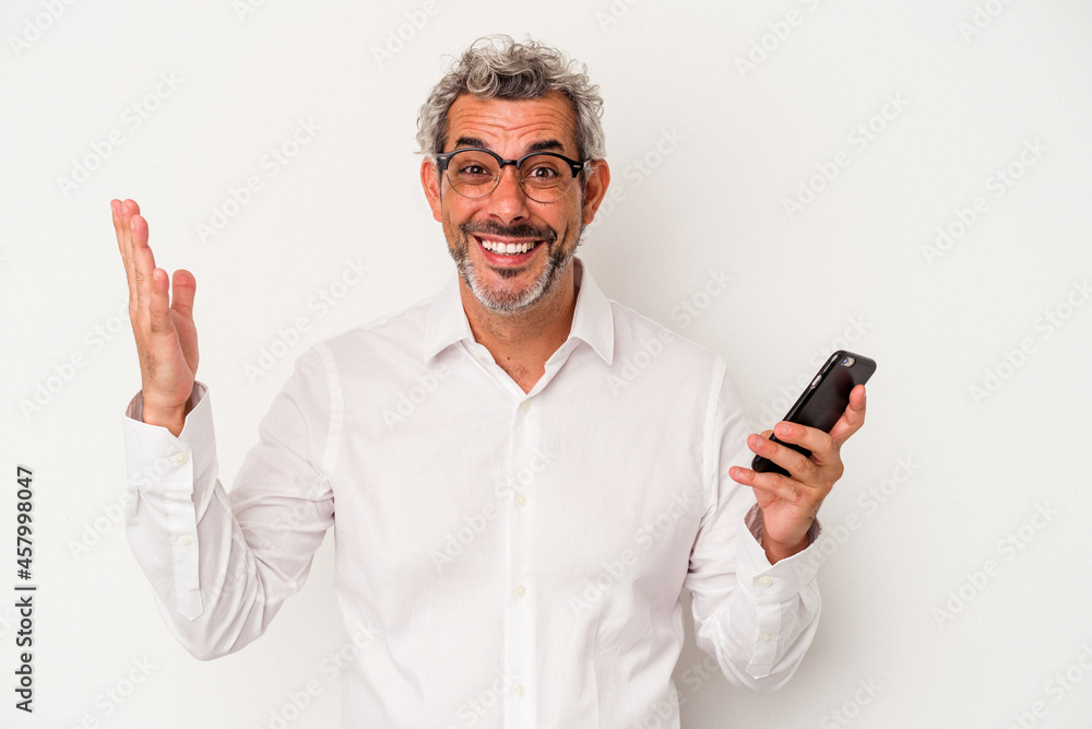 Middle age caucasian business man holding a mobile phone isolated on white background receiving a pleasant surprise, excited and raising hands. Middle age caucasian business man holding a mobile phone isolated on white background receiving a pleasant surprise, excited and raising hands.