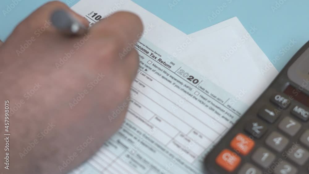A person calculation taxes and filling 1040 Tax Form. Closeup of man