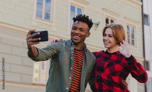 Young mixed couple making selfie for soial networks outdoors in town. photo