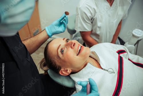 Caucasian female lying on doctors bed while nurse uses dental tools to remove dirt