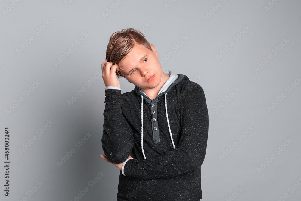 Portrait of a young man thinking over an idea, standing over grey background Portrait of a young man thinking over an idea, standing over grey background