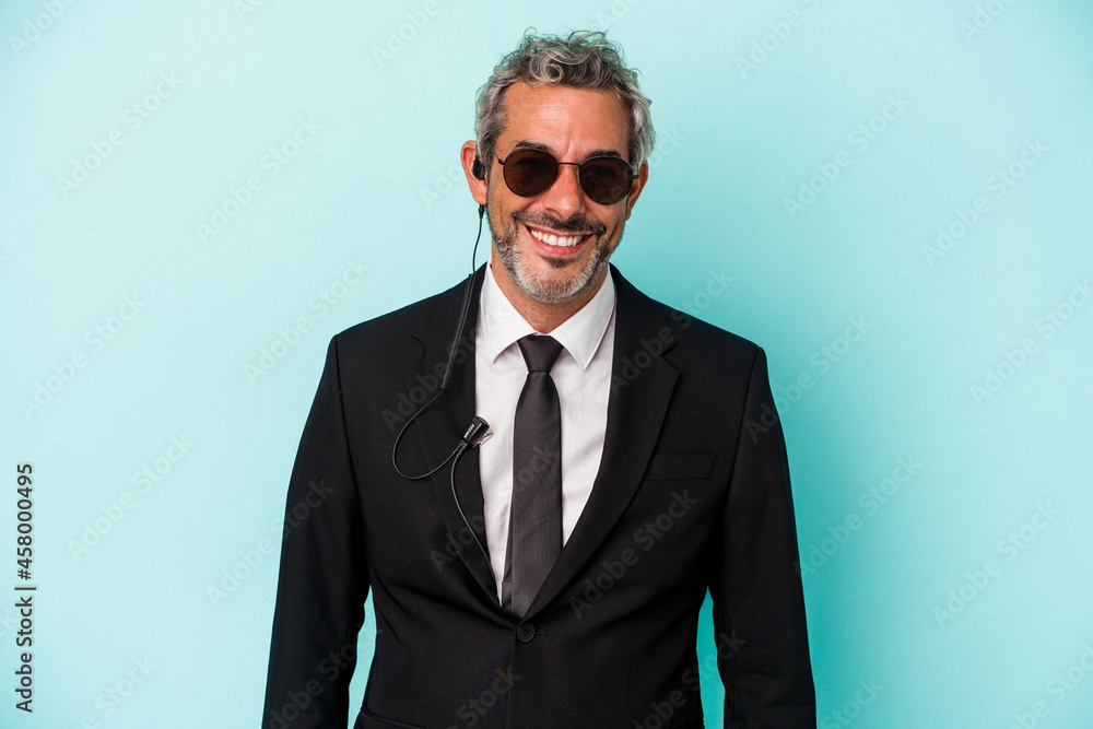 Middle age bodyguard caucasian man isolated on blue background happy, smiling and cheerful. Middle age bodyguard caucasian man isolated on blue background happy, smiling and cheerful.