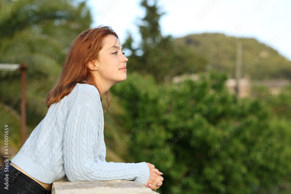 Woman contemplating views from balcony of rural house