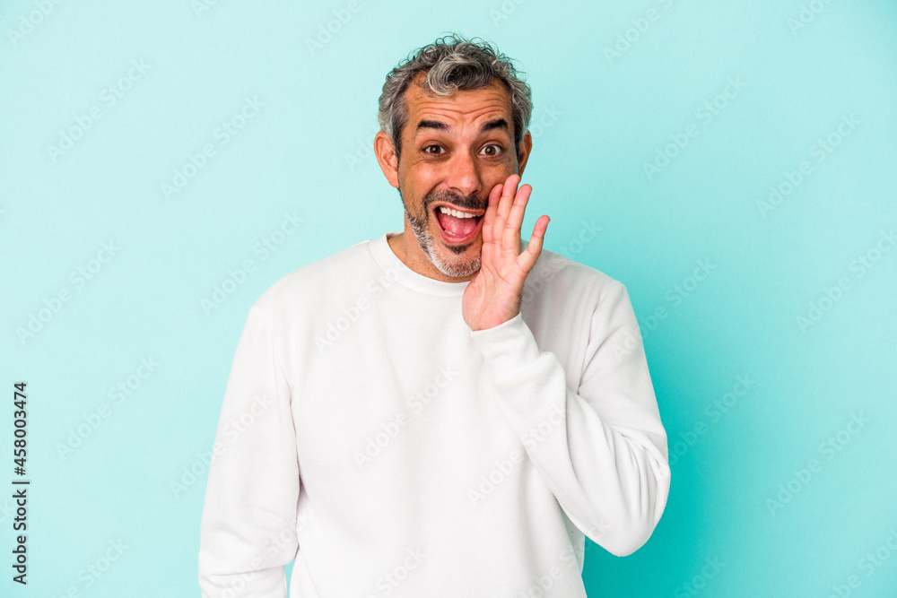Middle age caucasian man isolated on blue background shouts loud, keeps eyes opened and hands tense. Middle age caucasian man isolated on blue background shouts loud, keeps eyes opened and hands tense.