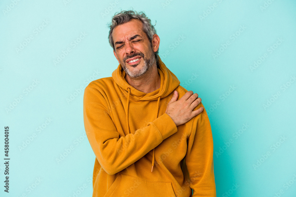Middle age caucasian man isolated on blue background  having a shoulder pain.