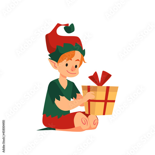 Cute christmas boy elf helper santa claus sit on floor with holiday present.