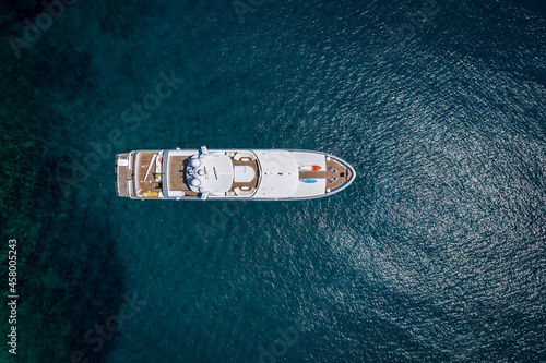 Aerial top down view of a luxury yacht over turquoise sea © moofushi