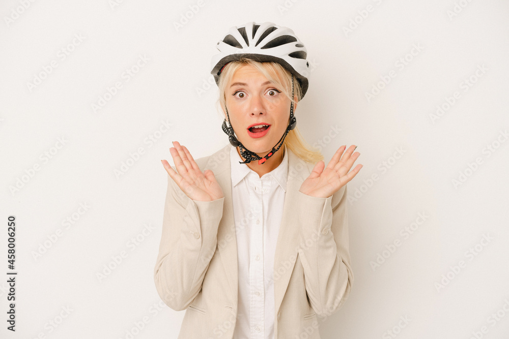 Young business Russian woman holding bike helmet isolated on white background surprised and shocked. Young business Russian woman holding bike helmet isolated on white background surprised and shocked.