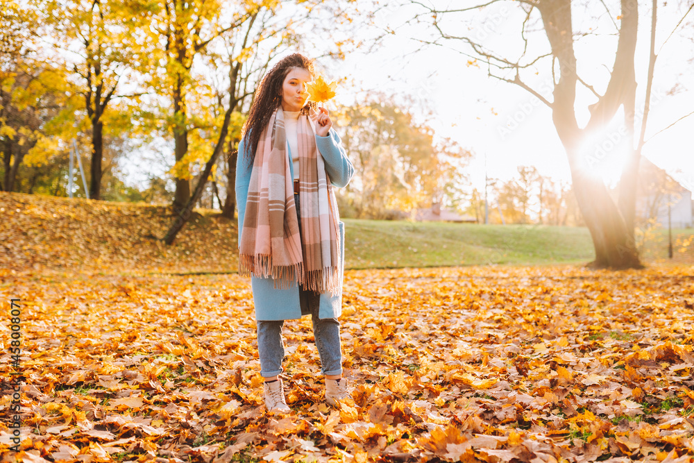 Happy smiling woman wearing brown boots, blie coat and jeans walk in park or forest with autumn yellow foliage Happy smiling woman wearing brown boots, blie coat and jeans walk in park or forest with autumn yellow foliage