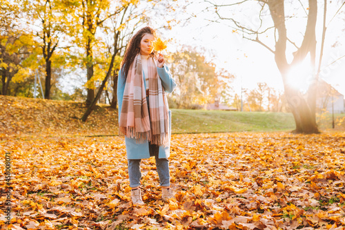 Happy smiling woman wearing brown boots, blie coat and jeans walk in park or forest with autumn yellow foliage photo