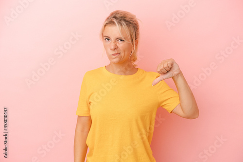Young Russian woman isolated on pink background showing thumb down, disappointment concept.