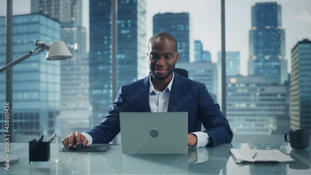 Portrait of Thoughtful Black Businessman Working on Laptop Computer in His Big City Office. Charismatic Digital Entrepreneur does Data Analysis for e-Commerce Strategy assessment. Zoom In Front View Portrait of Thoughtful Black Businessman Working on Laptop Computer in His Big City Office. Charismatic Digital Entrepreneur does Data Analysis for e-Commerce Strategy assessment. Zoom In Front View