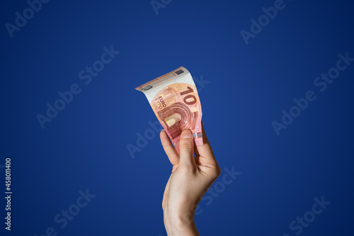  Hand holding a 10 Euro bill isolated on blue background