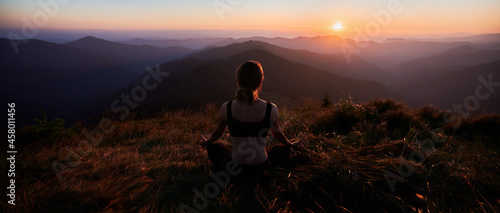 Photography Back view of woman practicing yoga in the mountains
