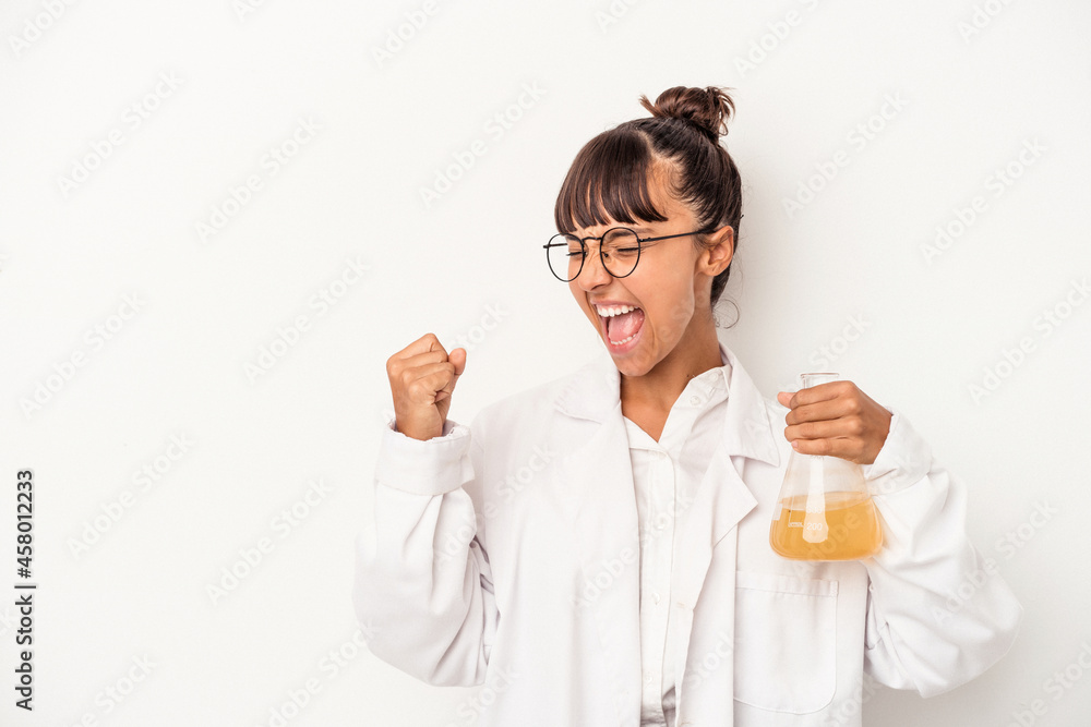 Young mixed race scientist woman holding a test tube isolated on white background raising fist after a victory, winner concept. Young mixed race scientist woman holding a test tube isolated on white background raising fist after a victory, winner concept.